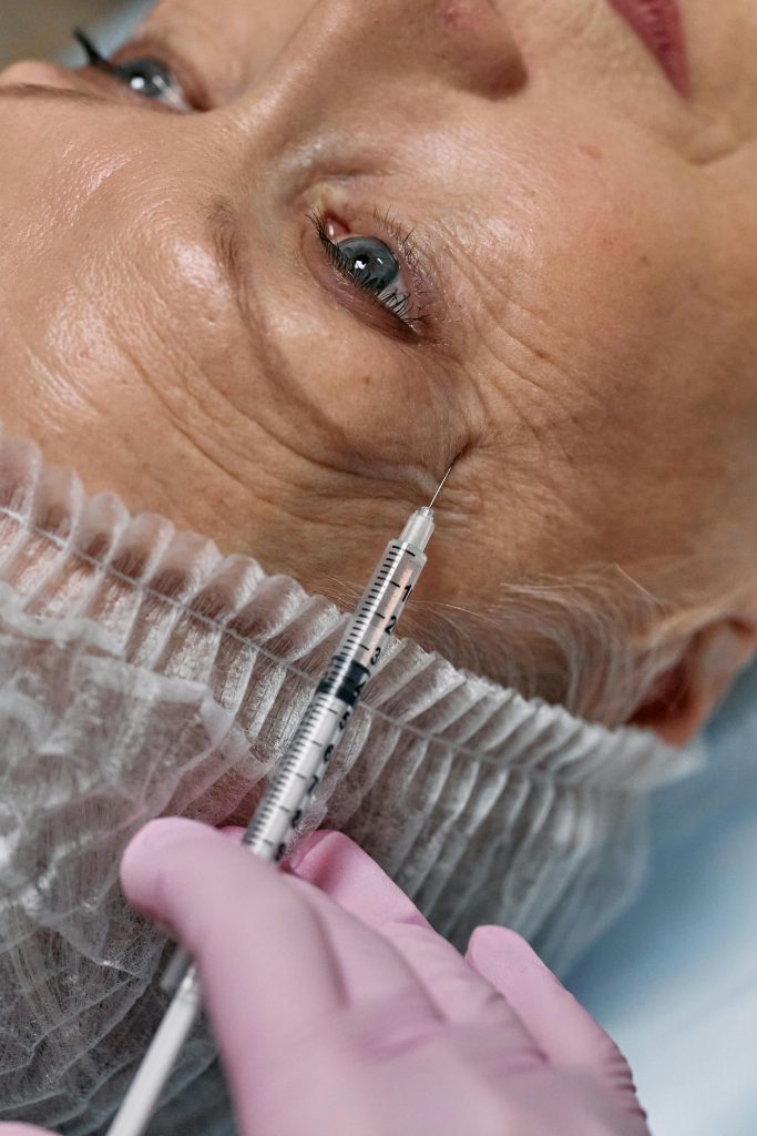 Close-up view of a senior woman receiving an anti-aging facial injection in a clinic.